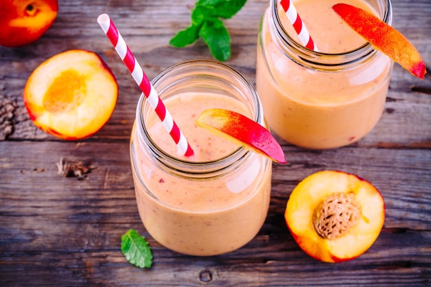 Nectarine smoothies in a mason jar with mint on wooden rustic background