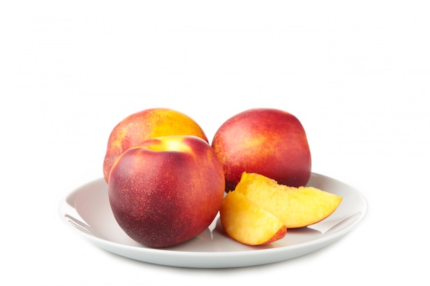 Nectarines in grijze plaat die op wit wordt geïsoleerd