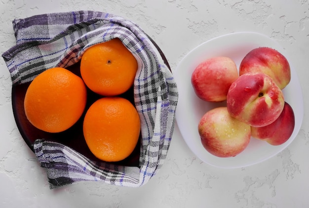 Нектарины и апельсины в тарелке свежих фруктов