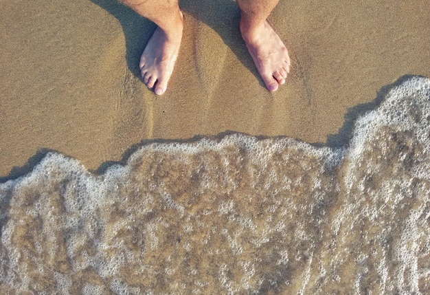 Nederig gedeelte van de man op het zand op het strand