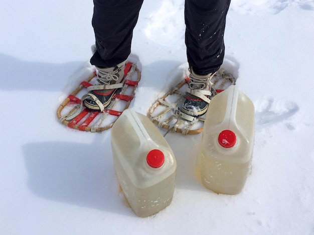 Foto nederig gedeelte van de persoon met op sneeuw staande containers