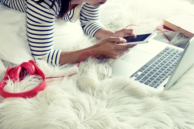 Foto nederig gedeelte van de vrouw die thuis een laptop op het bed gebruikt