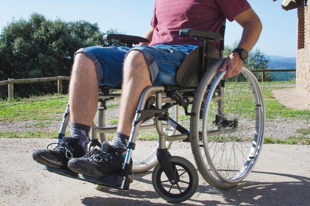 Foto nederig gedeelte van een man die buiten in een rolstoel zit