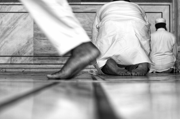 Foto nederig gedeelte van een man die langs mensen loopt die in een moskee bidden