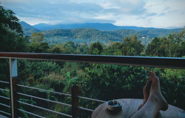 Foto nederig gedeelte van een man die tijdens de zonsondergang op een balkon op een asbak op tafel rust