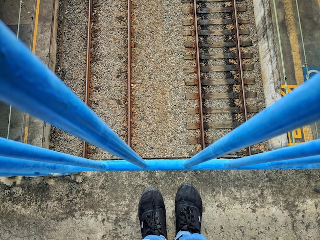 Foto nederig gedeelte van een persoon op een voetgangersbrug over spoorlijnen