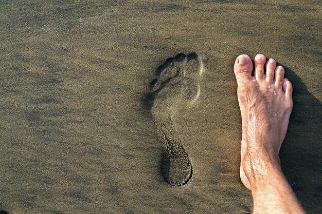 Foto nederig gedeelte van een persoon op het zand op het strand