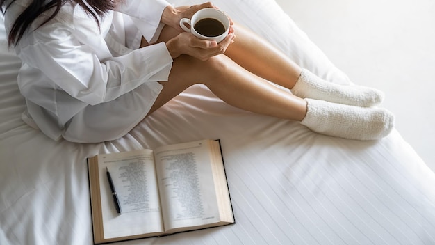 Nederig gedeelte van een vrouw die een koffiekop vasthoudt terwijl ze thuis zit