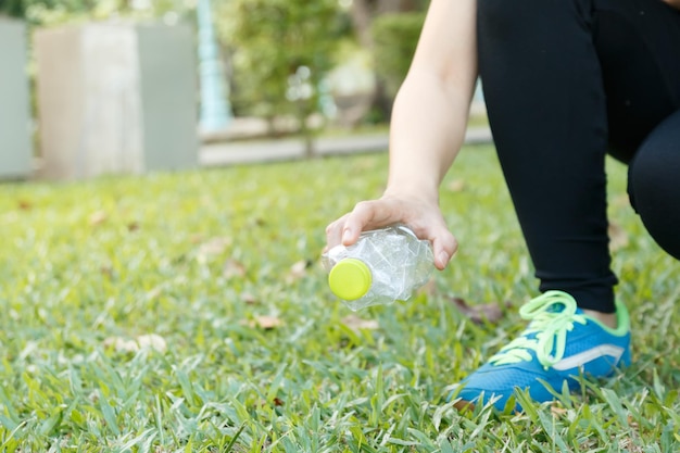 Nederig gedeelte van een vrouw die een plastic fles op het veld plukt
