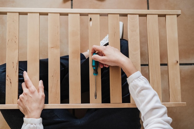 Nederig gedeelte van een vrouw die een schroefdraaier met meubels vasthoudt
