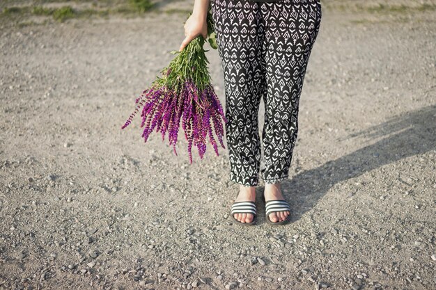 Foto nederig gedeelte van een vrouw die op een onverharde weg staat