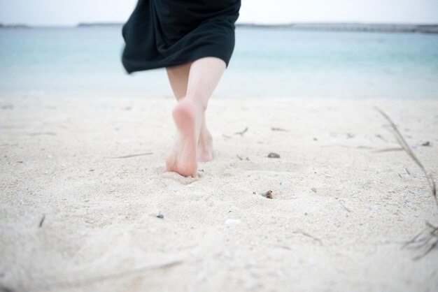 Nederig gedeelte van een vrouw die op het strand loopt