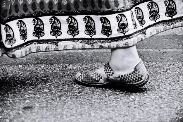 Foto nederig gedeelte van een vrouw in traditionele kleding die op het voetpad loopt