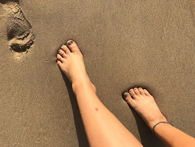 Nederig gedeelte van een vrouw op een zandstrand bij zonsondergang