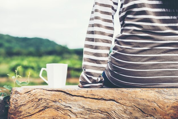 Foto nederig gedeelte van vrouw met koffiekop op tafel