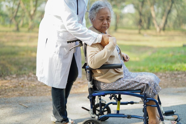 Foto nederige sectie van een arts die een oudere vrouw in een rolstoel in een park assisteert