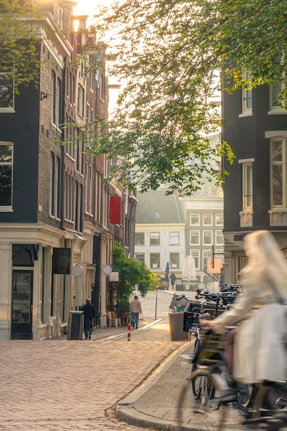 Nederland. Zonnige vroege ochtend op de straat van Amsterdam. Meisje op een fiets met bewegingsonscherpte en veel fietsen