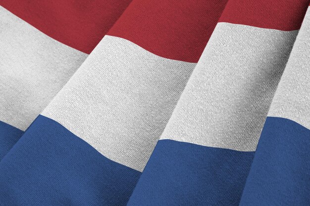 Nederlandse vlag met grote plooien die van dichtbij zwaaien onder het studiolicht binnenshuis De officiële symbolen en kleuren in banner