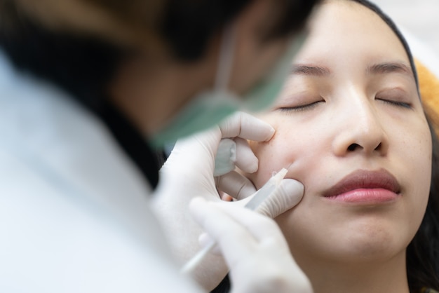 Needle mesotherapy in beauty clinic. Cosmetics injected to woman's face.