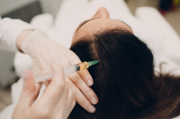 needle mesotherapy. cosmetic been injected in woman's head.