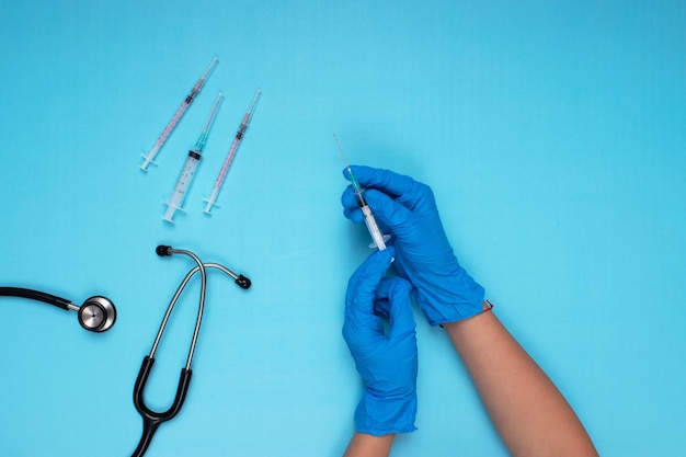 Needle stethoscope and other needles held in blue gloved hand on light blue background