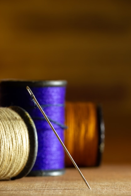 Photo needle and threads on wooden table.