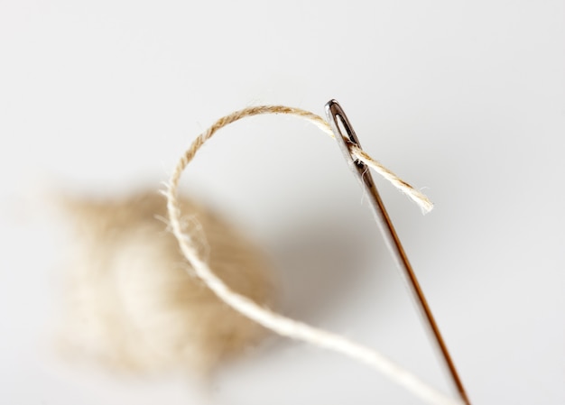 Needle with thread with ball on background