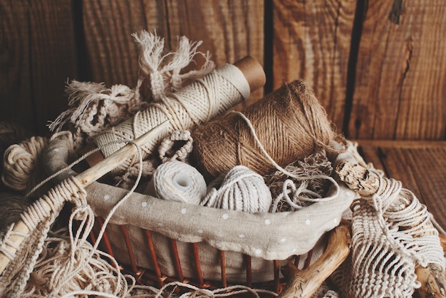 Needlework, macrame, knitting. Yarn and thread of natural colors in a wicker basket. Women's hobby.