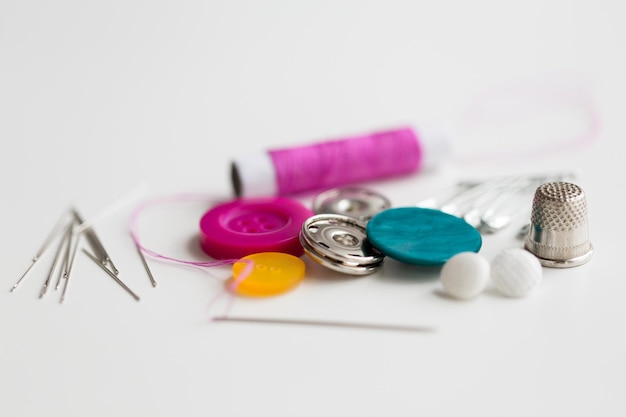 needlework and tailoring concept - sewing buttons, needles, pins and thread spool