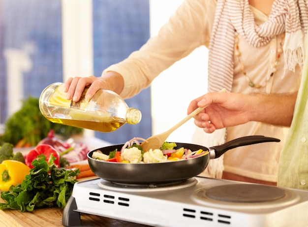 Ha bisogno di più olio. immagine ritagliata di una coppia che prepara la cena in cucina.