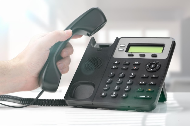 Neem contact met ons op voip telefoon voor communicatie contact met ons op en klantenservice ondersteuning vaste telefoon apparaat op kantoor hand nummer kiezen en telefoonhoorn vasthouden