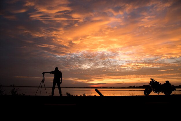 Neemt de silhouet Knappe Fotograaf een foto met professionele camera op de zonsondergang.