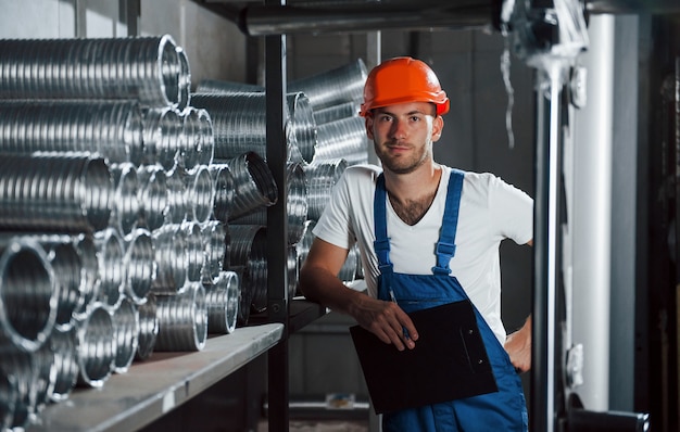 Neemt een pauze. Man in uniform werkt aan de productie. Industriële moderne technologie.