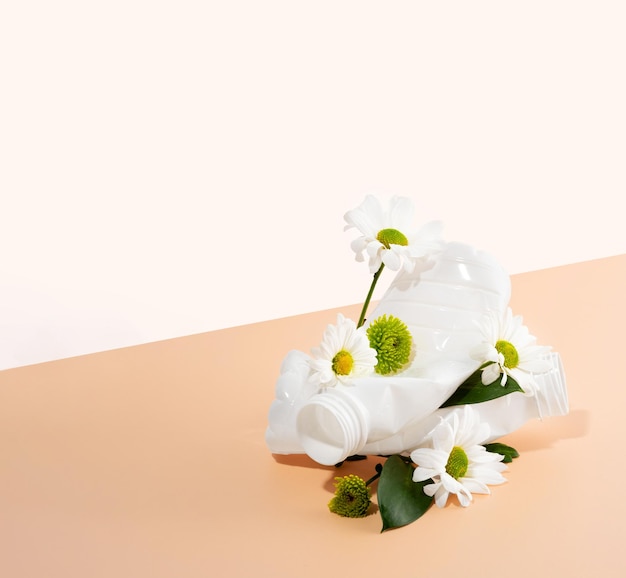 Negatieve impact op de natuur Plastic flessen verpletteren mooie bloemen op een perzikkleurige achtergrond Het concept van milieuschade Bodemvervuiling Het idee van plasticvervuiling