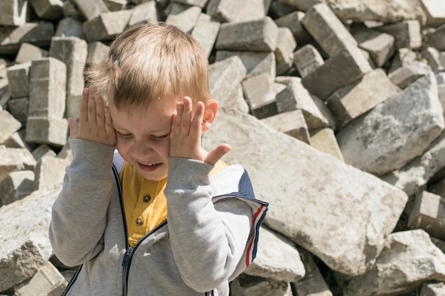 Negative emotions of the child fear depression selfdestruction
a small childboy covers his face with his hands against the
background of broken stones