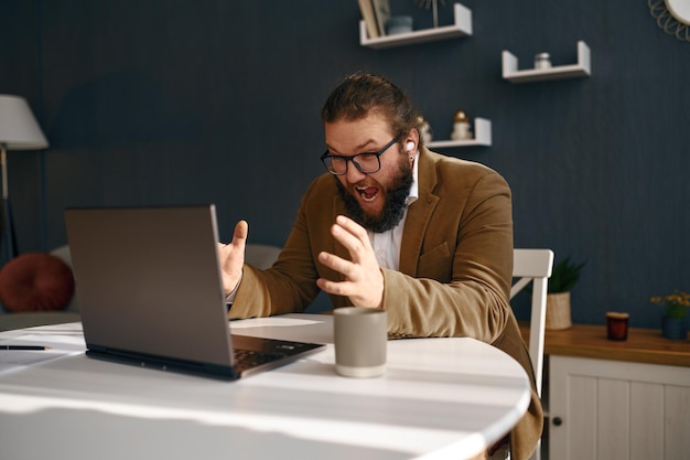 Ragazzo frustrato negativo che grida sullo schermo del laptop