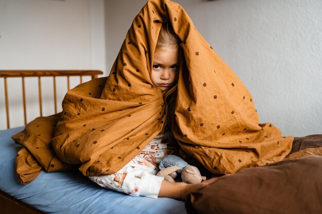 Negative human emotions reactions feelings a moody dissatisfied little girl sitting under a blanket