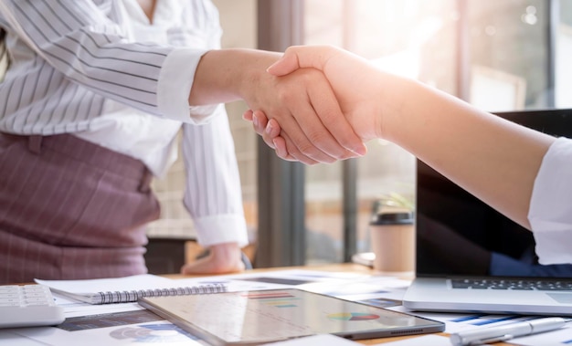 Negotiating business,Image of businesswomen Handshaking,happy with work, Handshake Gesturing People Connection Deal Concept. Cropped image. Young business people shaking hands in the office.
