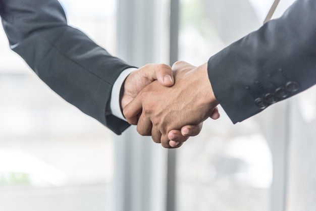 Foto negoziare gli affari, gli uomini d'affari si stringono la mano sul posto di lavoro.