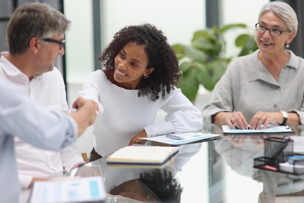 Negotiations in the office cheerful businesswoman shaking hands with colleague