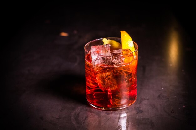 Negroni cocktail in a retro glass with ice and orange peel on a dark background