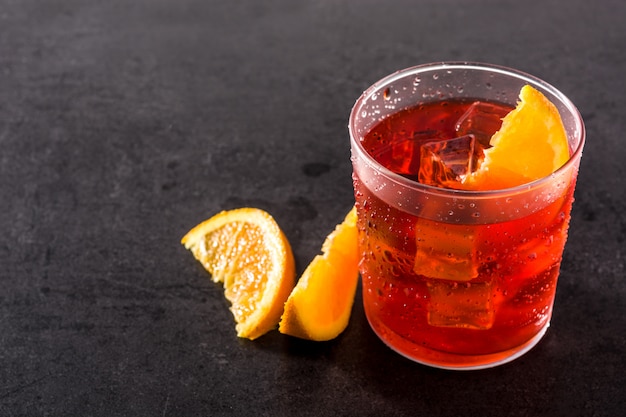 Negroni cocktail with piece of orange in glass on black, copyspace