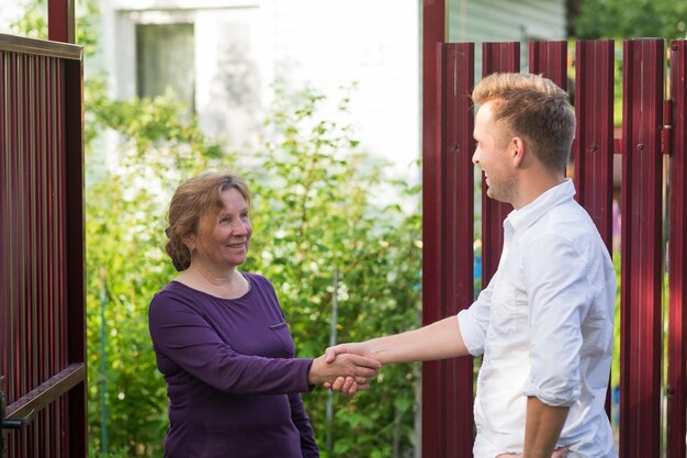 Neighbors discuss the news standing at the fence An elderly woman talking with a young man