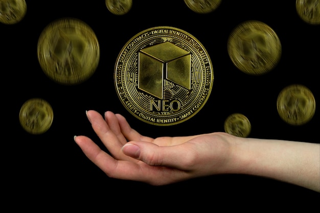 NEO coin and a mans hand on a black background