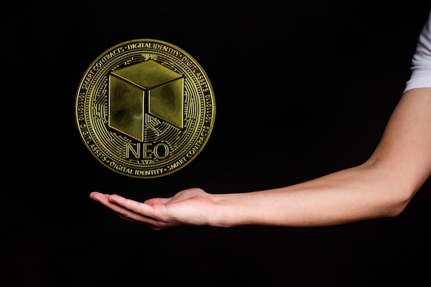 NEO coin and a mans hand on a black background