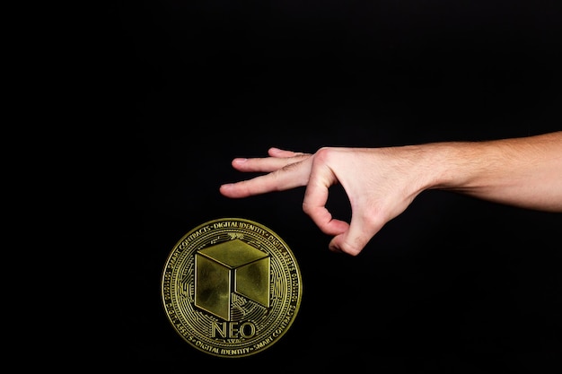 NEO coin and a mans hand on a black background