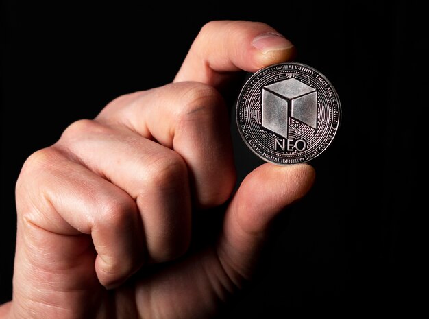 Neo shiny silver coin in male hand over black background