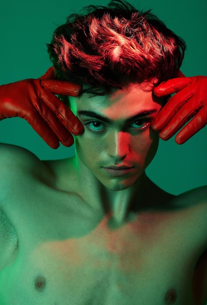 Neon creatief en gezichtsportret van mannequin met roodgroene verlichtingshouding en serieus licht voor artistieke expressie Creativiteitsindividualiteit en trendy man geïsoleerd op groene achtergrond
