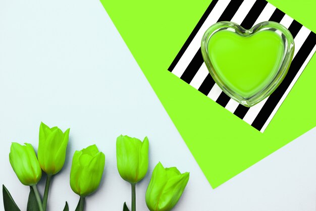 Neon groen hart en gele tulpen op een groene strepenachtergrond,