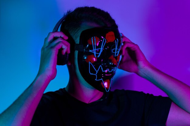 Neon portret van man met masker in koptelefoon, zwart t-shirt. Naar muziek aan het luisteren